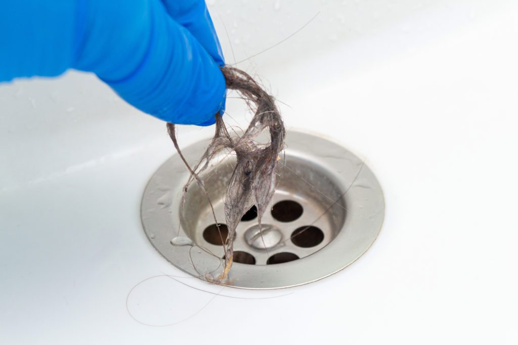 A Bonfe professional cleaning hair from a drain