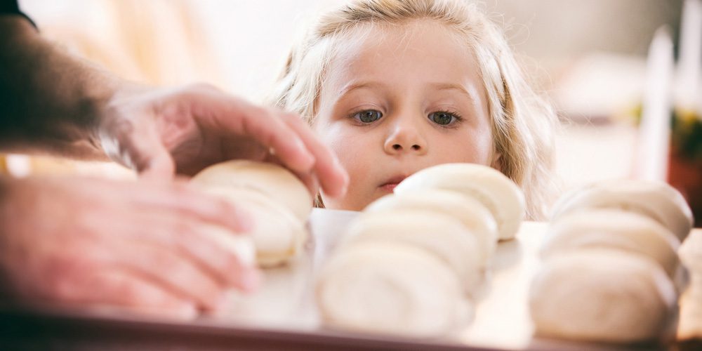 Child looking at rolls going into oven