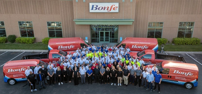 The entire Bonfe team standing with their service vehicles outside of their main office